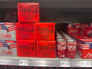 Cases and cans of Coco-Cola sodas.